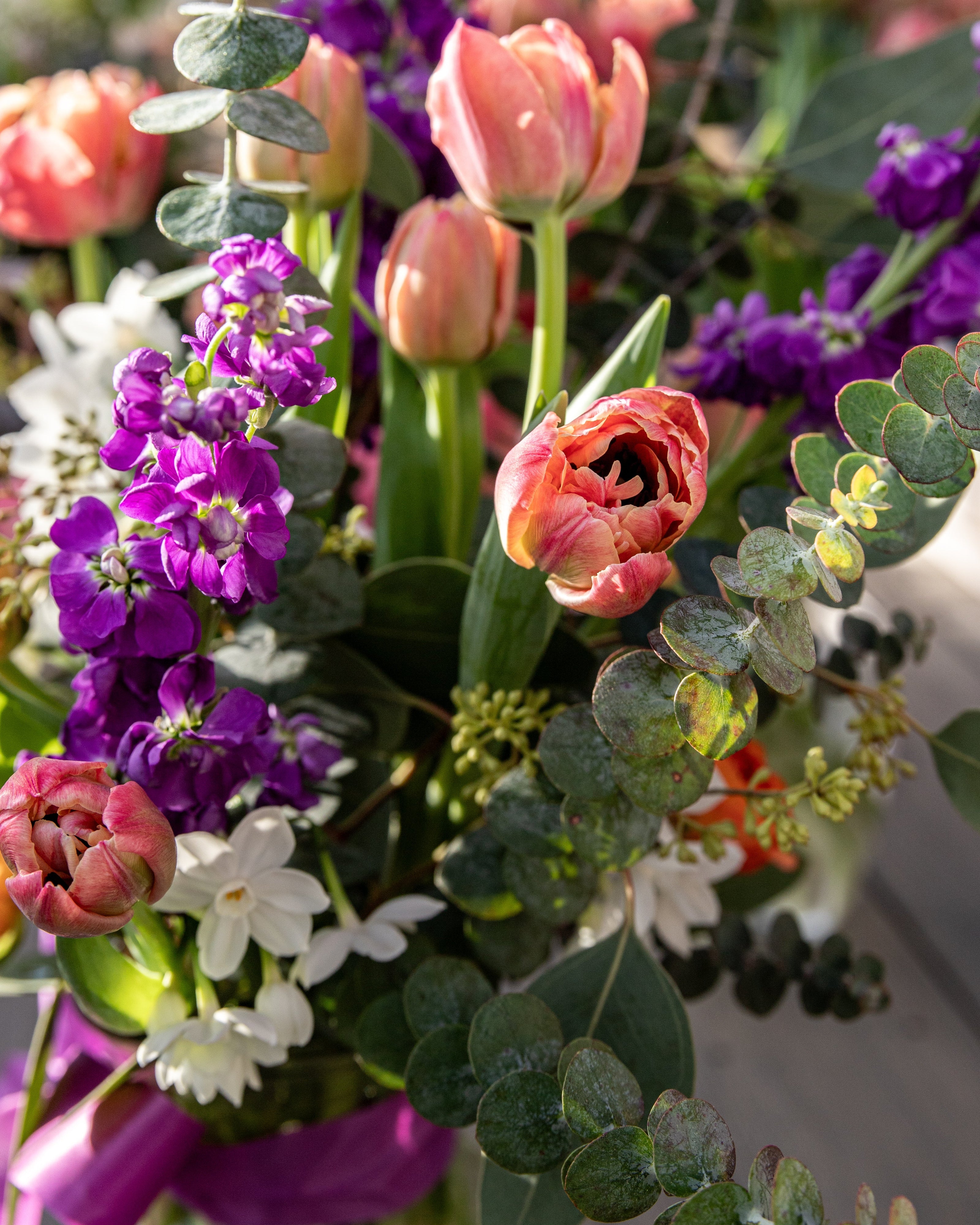The graceful-stem Bouquets & Arrangements for Delivery features a hand-tied mix of pink tulips, purple stock, white blooms, and eucalyptus leaves, beautifully arranged and ready to brighten any space.